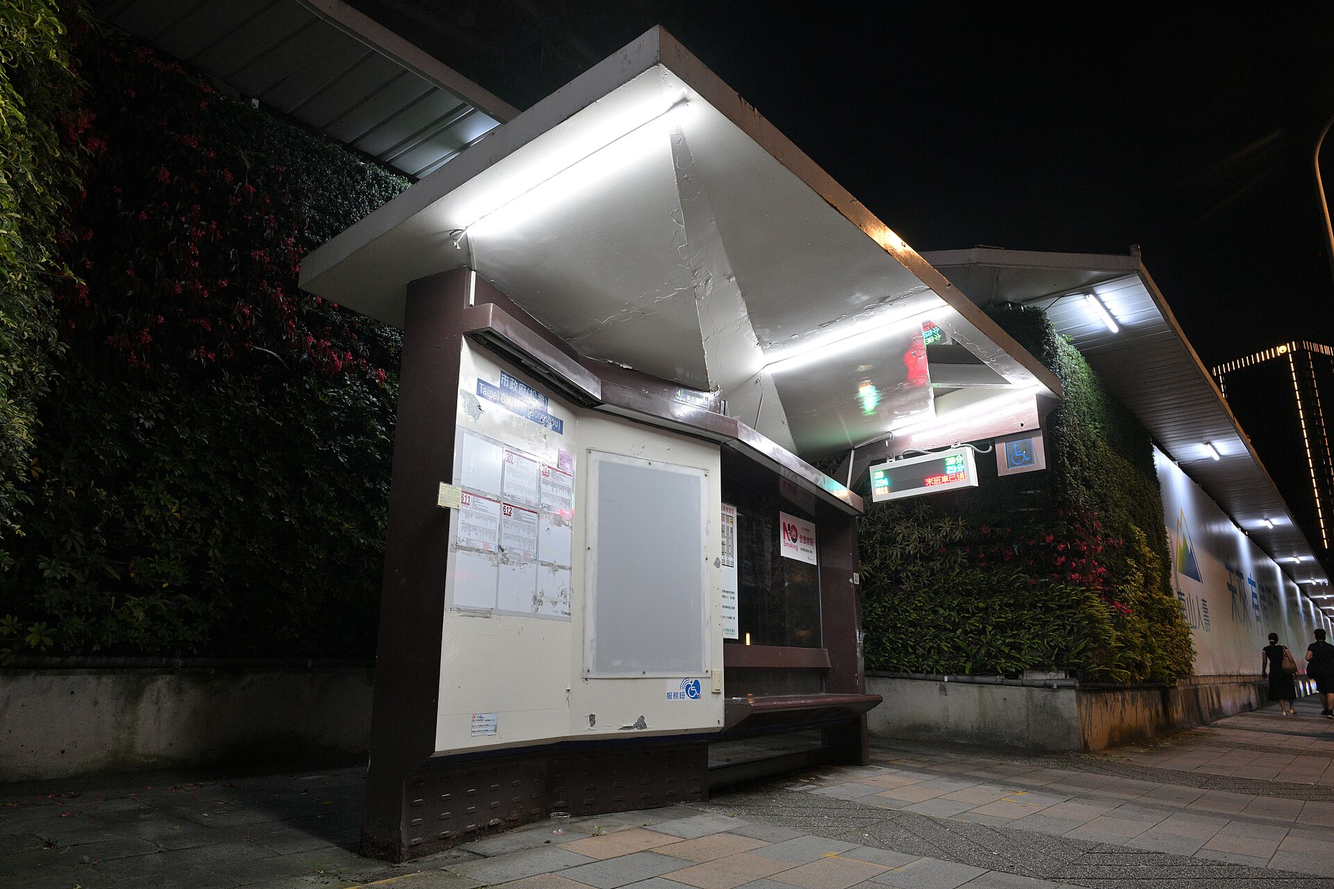 夜の台北市政府バス停、緑の壁面と発車案内板
