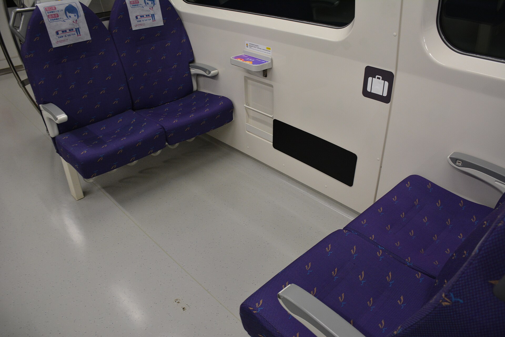 桃園機場捷運の直達車（エクスプレス）車内、紫色の座席と手荷物マークが描かれたドア横の壁面、乗客の姿はない