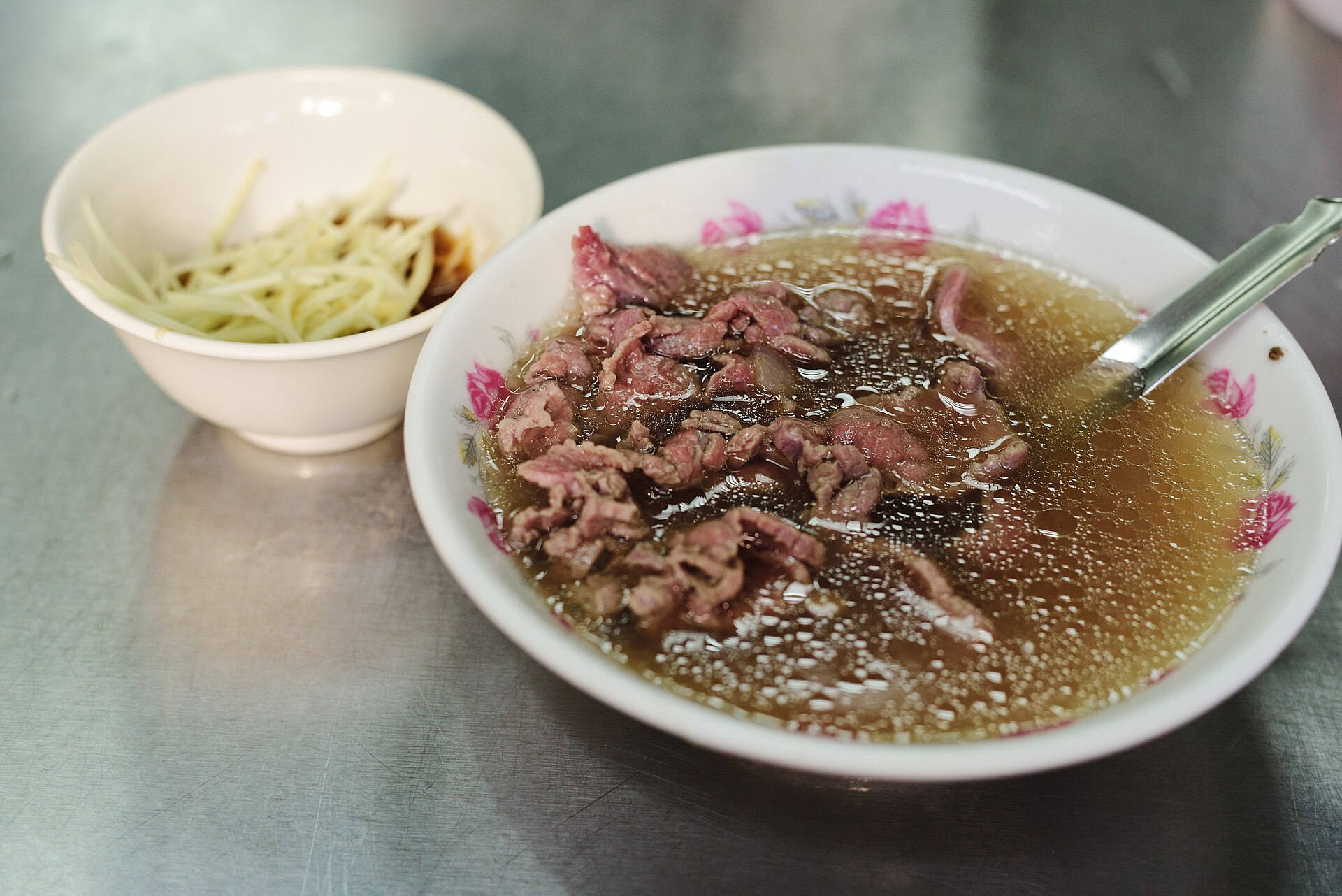 台南の朝ごはんの定番、牛肉湯の丼に浮かぶ薄切り牛肉とつけ合わせの生姜の器