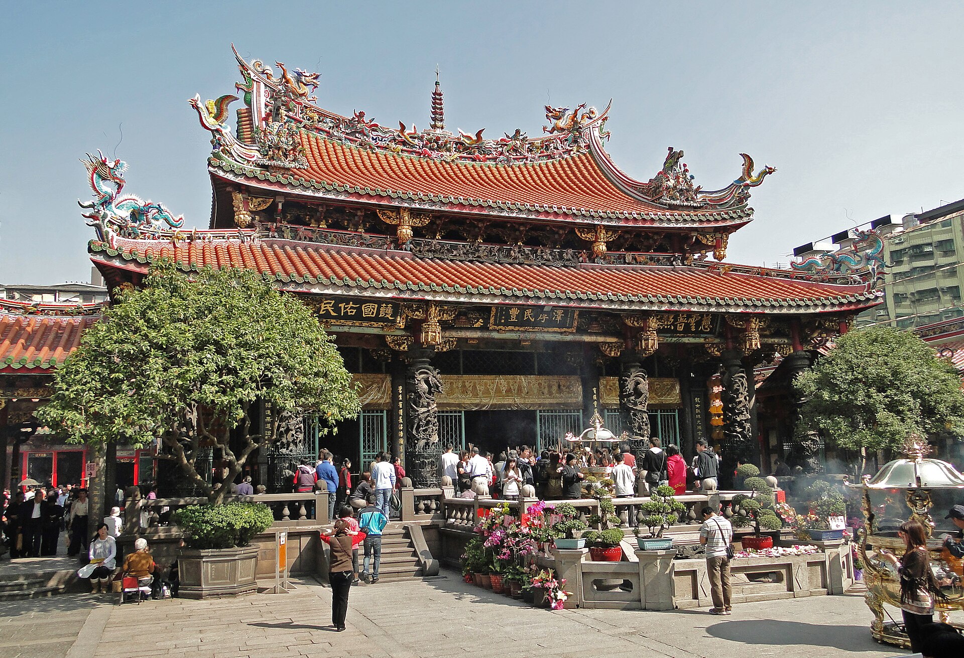 龍山寺の本堂正面、線香の煙が立ちのぼる中で参拝する人々